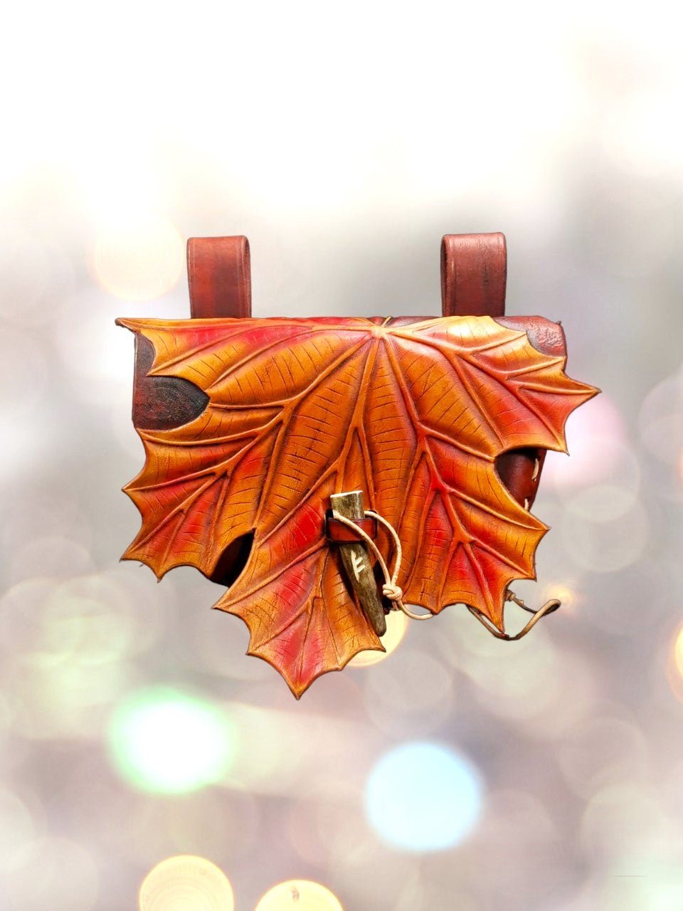 Focused image of the top handle and maple leaf detail on the leather bag, showcasing craftsmanship