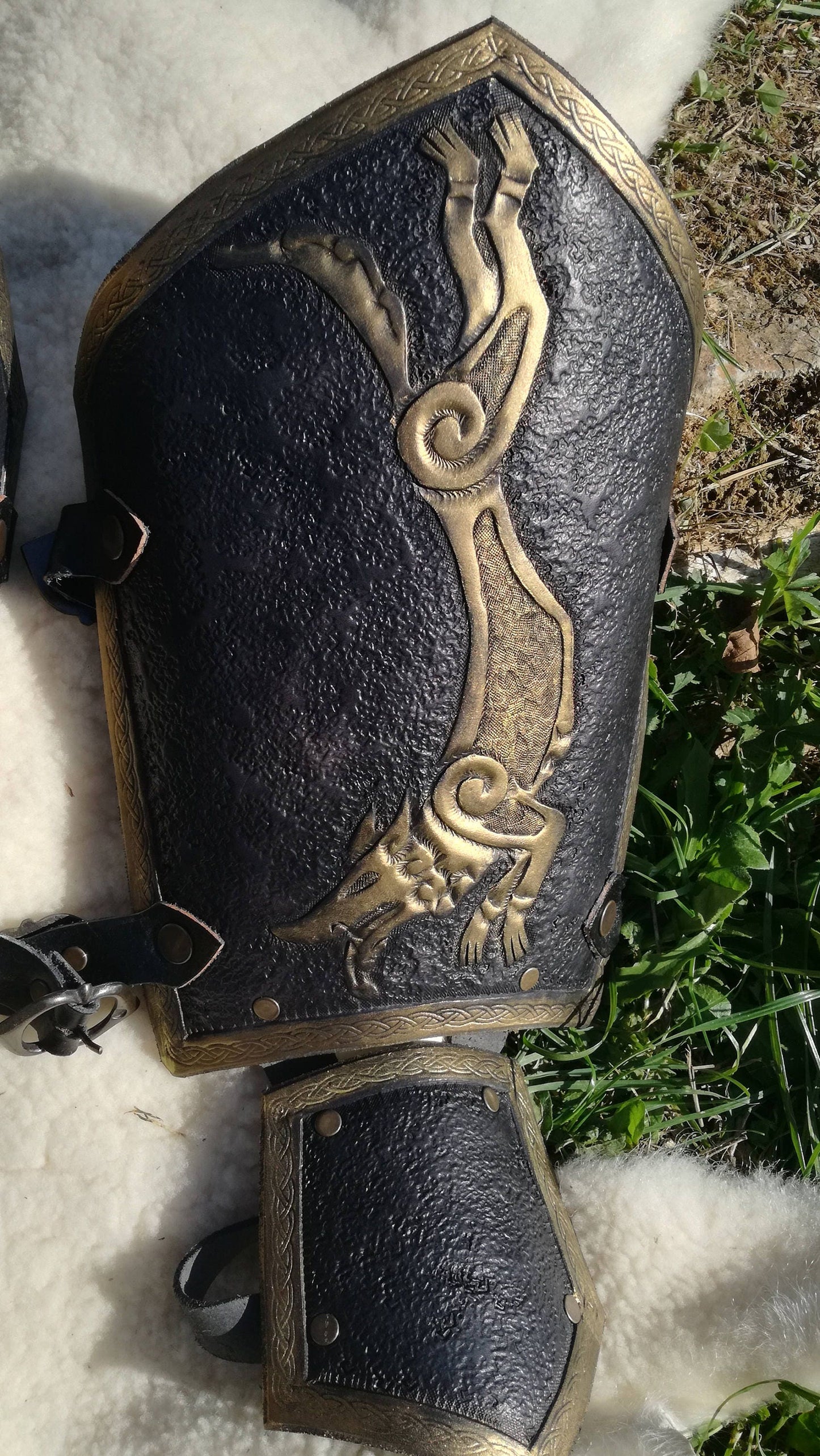 This black and gold medieval bracer is adorned with a hand-engraved wolf design, perfect for noble knights and fierce warriors. Its flexible construction allows for easy movement while maintaining a strong and commanding presence