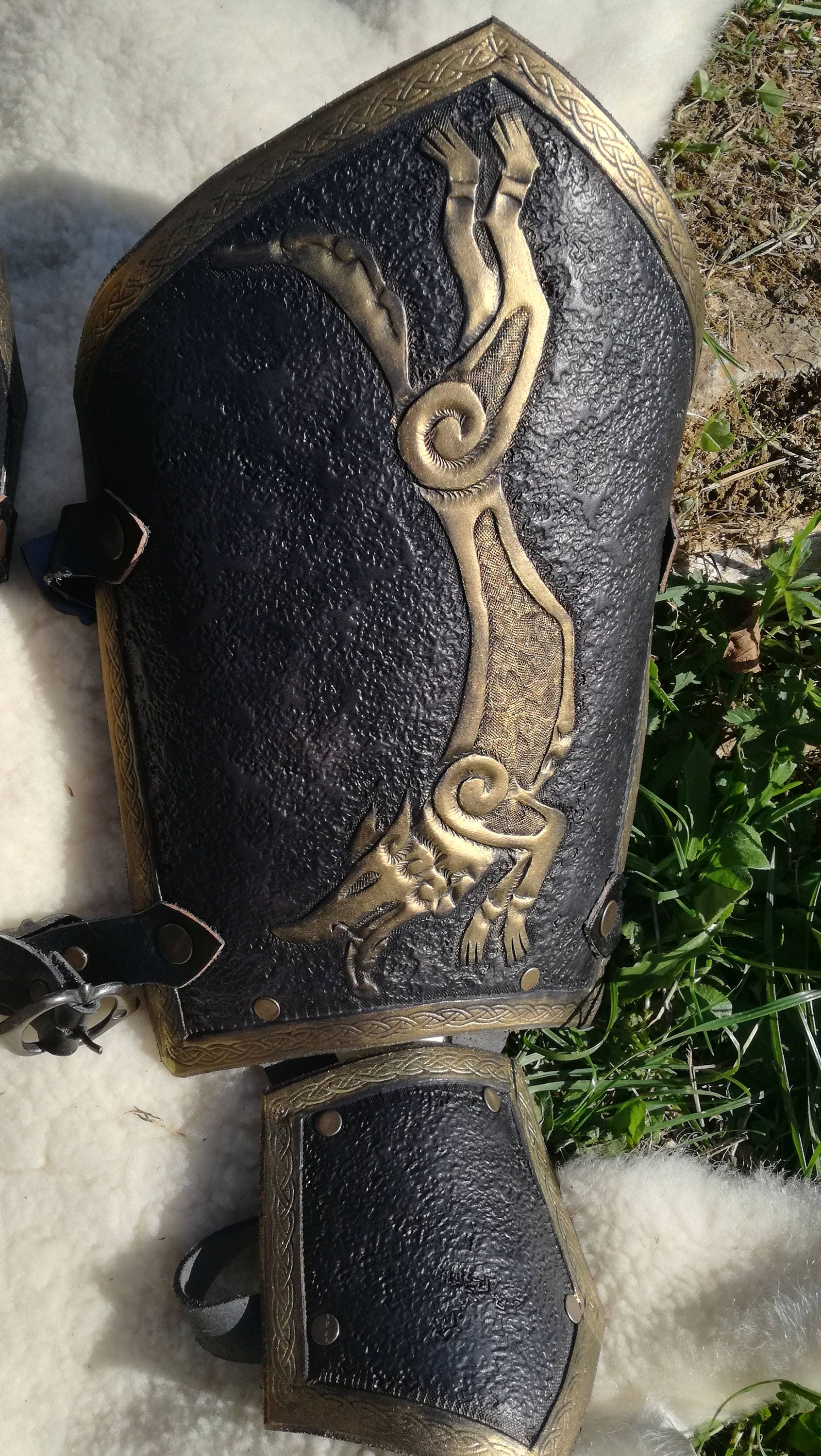 This black and gold medieval bracer is adorned with a hand-engraved wolf design, perfect for noble knights and fierce warriors. Its flexible construction allows for easy movement while maintaining a strong and commanding presence