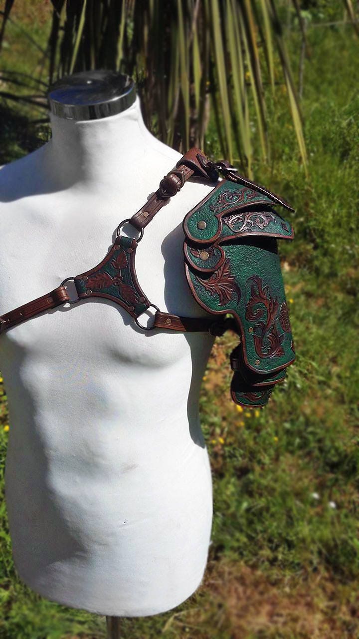 A pair of green and brown handcrafted leather spaulders, ideal for fantasy adventurers. Designed for comfort and movement, these engraved shoulder guards bring authenticity to any LARP or cosplay outfit. Fully customizable in color and design.