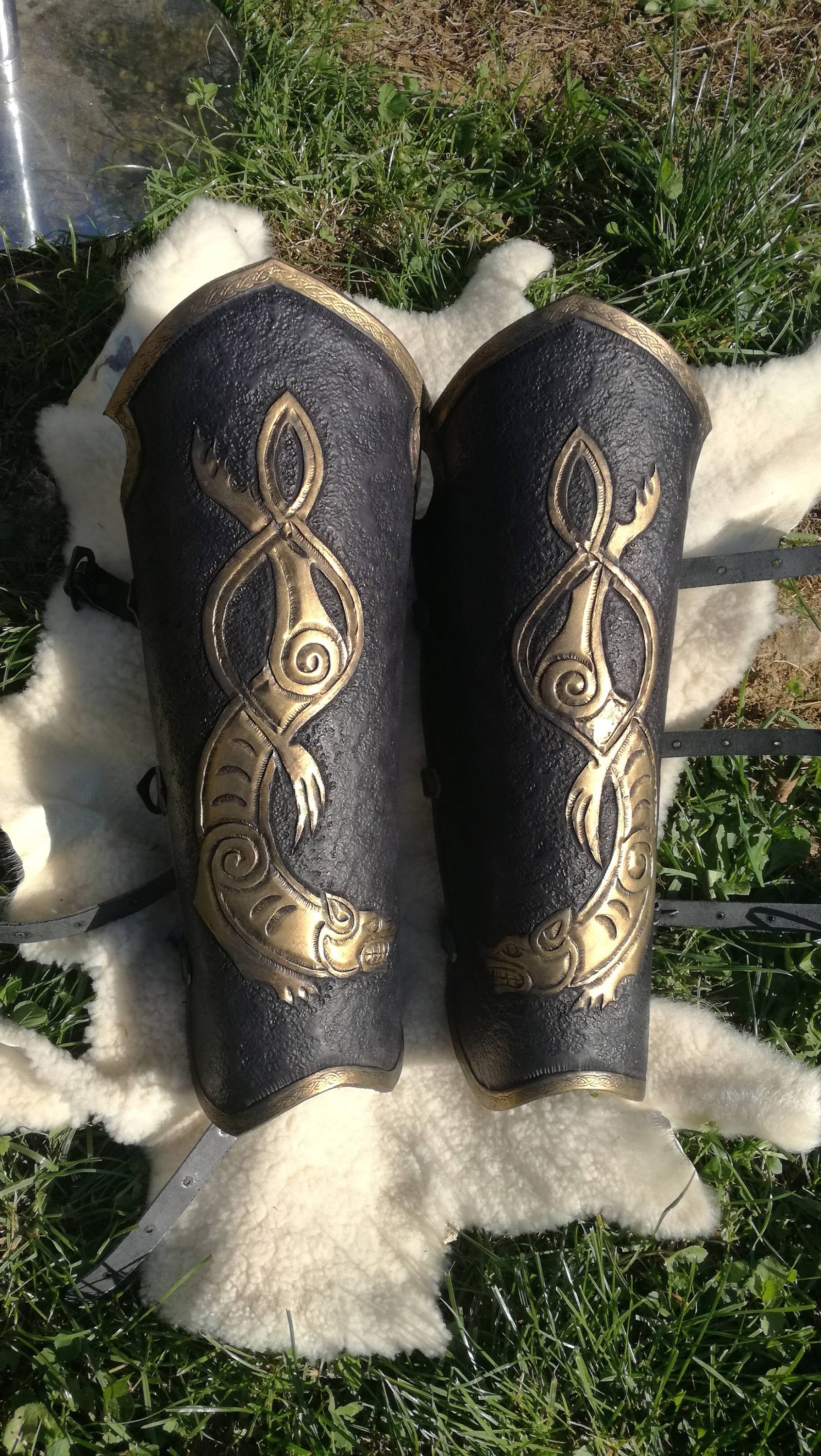 This black and gold knight-style bracers and greaves showcases a majestic engraved celtic wolf, crafted from durable leather. The elegant gold accents elevate the look, making it a premium choice for cosplay knights, medieval reenactors, and LARP warriors