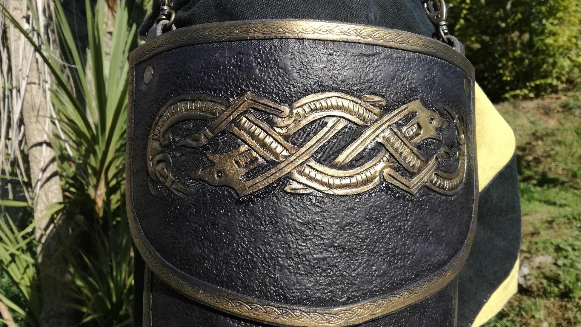 Detail of a tasset of the complete black and gold armor, meticulously handcrafted with a striking engraved wolf design. Made for medieval fantasy characters, this fully adjustable armor piece adds both protection and style to any warrior’s ensemble
