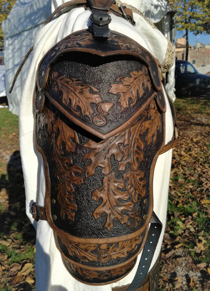 A light brown leather spaulder featuring hand-engraved oak leaves, symbolizing strength and endurance. The flexible and adjustable design makes it ideal for medieval fantasy role-playing, theater, and cosplay